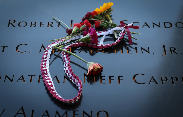 Flowers and a necklace are pictured left near the inscribed names of victims at the the north reflecting pool during a ceremony marking the 23rd anniversary of the September 11, 2001 attacks on the World Trade Center at the 9/11 Memorial and Museum in Manhattan, New York City on September 11, 2024. (Photo by Mike Segar/Reuters)