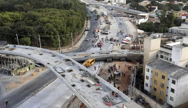 Rescue workers try to reach vehicles trapped underneath a bridge that collapsed while under construction in Belo Horizonte July 3, 2014. An unfinished overpass collapsed in the Brazilian World Cup host city of Belo Horizonte on Thursday, killing at least two people, emergency officials said. (Photo by Carlos Greco/Reuters)
