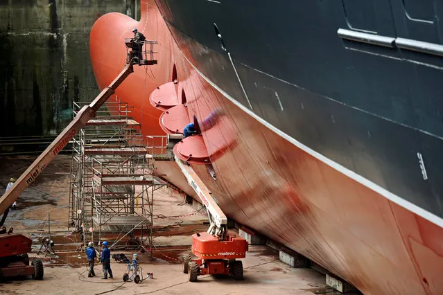 Workers paint and repair the ocean liner Queen Mary II in a dock at Blohm&Voss shipyard in Hamburg, Germany, June 14, 2016. The mighty Queen Mary 2 is just days away from setting sail after the most expensive refurbishment of any ship in history. Tens of millions of pounds have been spent on the 151,200-tonne ship as 2,500 workers complete the month-long major interior overhaul. (Photo by Fabian Bimmer/Reuters)