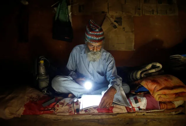 Durga Kami, 68, who is studying in the tenth grade at Shree Kala Bhairab Higher Secondary School, uses a torch to read a book during a power cut, at his one-room house in Syangja, Nepal, June 4, 2016. (Photo by Navesh Chitrakar/Reuters)