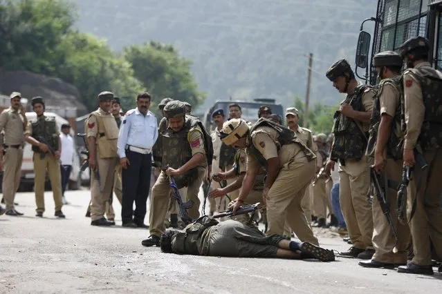 Indian paramilitary soldiers check the body of a suspected rebel after a gunbattle on the Jammu- Srinagar highway at Narsoo Nallah, near Udhampur, India, Wednesday, August 5, 2015. Two paramilitary soldiers and one suspected rebel were killed in Indian-controlled Kashmir Wednesday after a convoy of paramilitary troops was ambushed in the troubled region, police said. (Photo by Channi Anand/AP Photo)