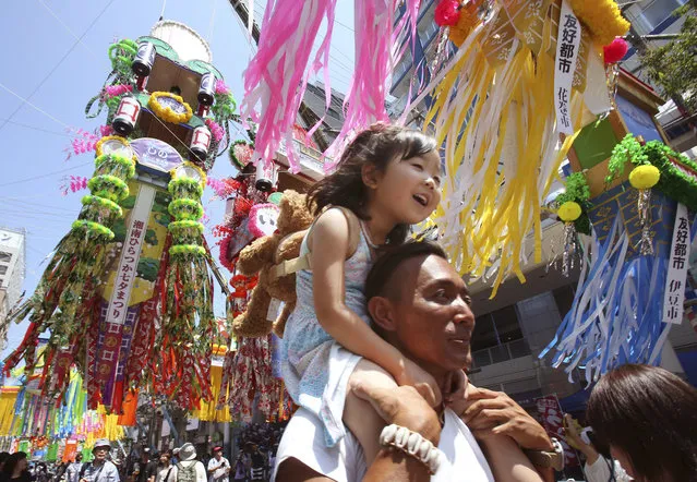 A girl is carried on her father's shoulder as people walk under colorful paper streamers decorated at a shopping street to celebrate the Tanabata Star Festival in Hiratsuka, near Tokyo, Friday, July 7, 2017. According to legend, deities Orihime (Vega) and her lover Hikoboshi (Altair), separated by the Milky Way, are allowed to meet only once a year on July 7. People in the country celebrate the festival by writing wishes on strips of paper and hanging them under bamboo trees. (Photo by Koji Sasahara/AP Photo)