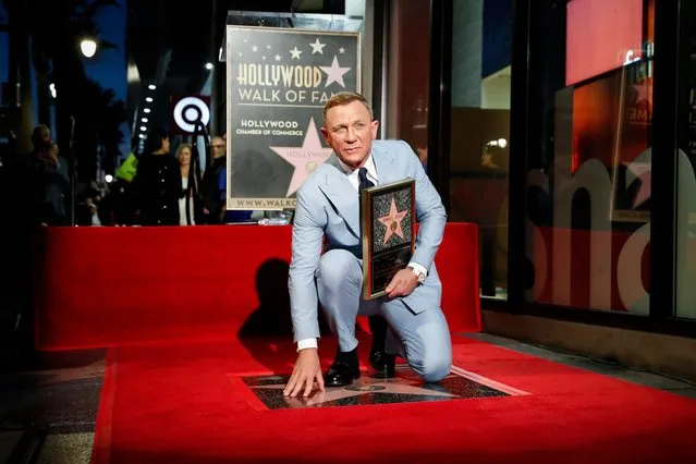 British actor Daniel Craig kneels atop his new star on the Hollywood Walk of Fame while holding a replica of the star during a c​eremony in his honor in Los Angeles, California, USA, 06 October 2021. (Photo by Caroline Brehman/EPA/EFE)