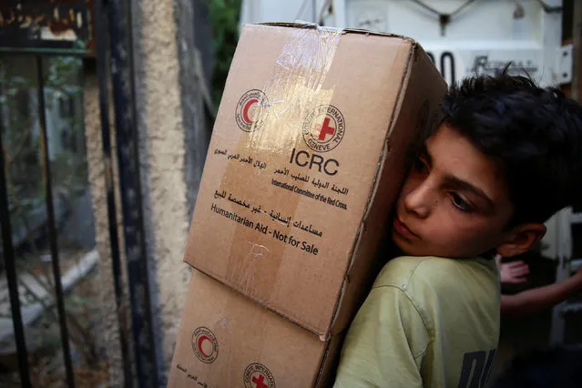 A boy unloads aid parcels in the rebel-held besieged town of Zamalka, in the Damascus suburbs, Syria June 29, 2016. (Photo by Bassam Khabieh/Reuters)