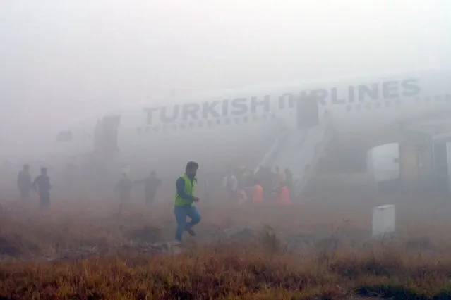 Passengers leave a Turkish Airlines plane which skidded off the runway on landing at Kathmandu airport in the Nepalese capital Kathmandu on March 4, 2015. Aviation officials said no one on board was injured, although one witness described how terrified passengers leapt from their seats as the cabin filled with smoke after the plane skidded to a halt. (Photo by Dikesh Malhotra/AFP Photo)