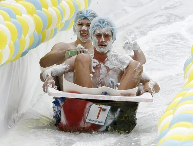 Participants slide down inside a bath along a chute to cross a pool of water and foam during the “Letniy Gornoluzhnik” (Summer mountain puddle rider) festival at the Bobroviy Log Fun Park near the Siberian city of Krasnoyarsk, Russia, August 23, 2015. (Photo by Ilya Naymushin/Reuters)
