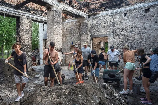 Volunteers clean up the House of a Culture in the village of Yahidne, which was heavily damaged during Russia's attack on Ukraine, in Chernihiv region, Ukraine on July 23, 2022. Members of the volunteers' movement Repair Together travel over regions, which were under Russian occupation and help local residents to clean up damaged buildings under accompaniment of electronic music. (Photo by Viacheslav Ratynskyi/Reuters)