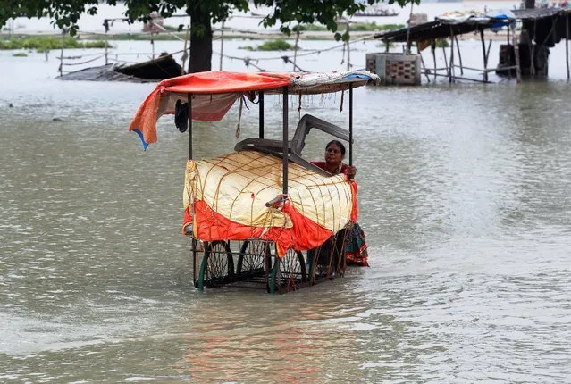 A woman pushes her cart through a flooded road after heavy rains in Allahabad, India, July 15, 2016. (Photo by Jitendra Prakash/Reuters)