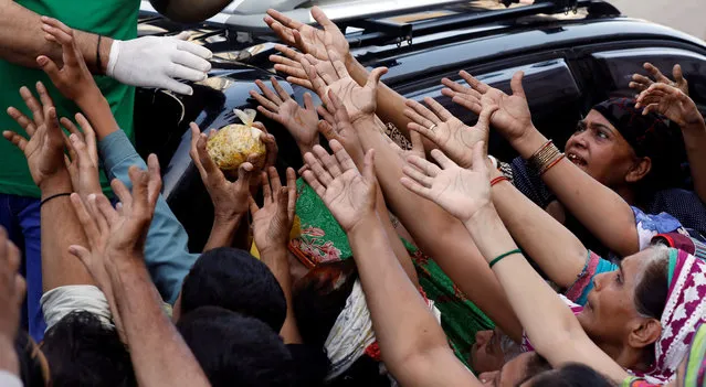 People reach out to get a charity food handout during a lockdown after Pakistan shut all markets, public places and discouraged large gatherings amid an outbreak of the coronavirus disease (COVID-19), in Karachi, Pakistan, March 30, 2020. (Photo by Akhtar Soomro/Reuters)