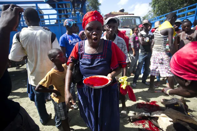 In this July 24, 2016 photo, a female Voodoo priestess carries a bowl overflowing with the blood of a recently sacrificed bullock during the annual Voodoo celebration in Plaine-du-Nord, Haiti. The pilgrims who trek to Plaine-du-Nord take ritual baths of mud, light candles and make offerings to the spirits. Voodoo evolved in the 17th century among African slaves and incorporates elements of the Roman Catholic faith that was forced upon them by French colonizers. (Photo by Dieu Nalio Chery/AP Photo)