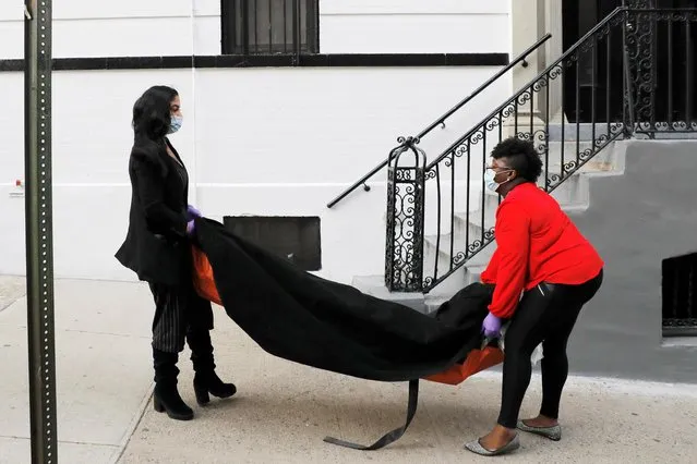 Alisha Narvaez, 36, the manager and Nicole Warring, 33, a Resident Funeral Director at International Funeral & Cremation Services, a funeral home in Harlem, carry a deceased person into the basement area, where bodies are stored and prepared for funeral services, during the coronavirus disease (COVID-19) outbreak, in Manhattan, New York City, New York, U.S., April 2, 2020. (Photo by Andrew Kelly/Reuters)