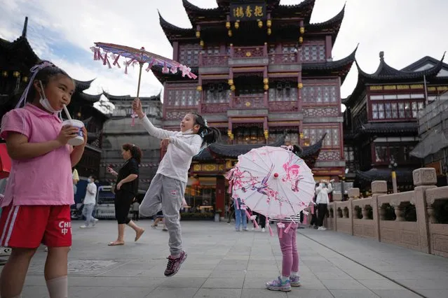 Girls play with paper umbrellas before the Mid-Autumn festival at the Yu Garden, following the coronavirus disease (COVID-19) outbreak, in Shanghai, China on September 9, 2022. (Photo by Aly Song/Reuters)