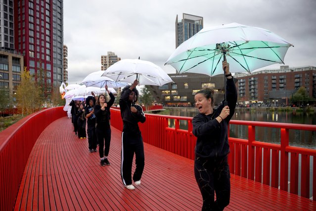 Performers from Cirque Bijou carry umbrellas along a 170m red pedestrian footbridge designed by British architect Asif Khan during an event to mark its opening to the public in Canada Water, London on November 2, 2024. (Photo by Jack Taylor for the Times)