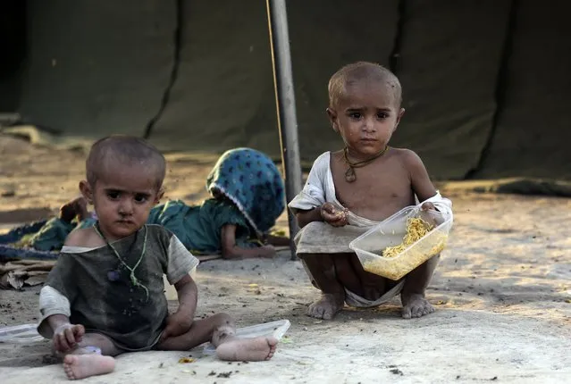 Children displaced by flooding from monsoon rains eat food at a temporary tent housing camp  for flood victims and organized by the China government, in Sukkur, Pakistan, Wednesday, September 7, 2022. (Photo by Fareed Khan/AP Photo)