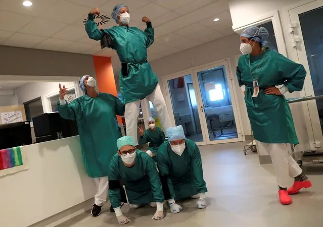 Healthcare workers wearing face masks, gloves and overall suits form a human pyramid to relax in the coronavirus disease (COVID-19) intensive care unit at the MontLegia CHC Hospital in Liege, Belgium, May 15, 2020. (Photo by Yves Herman/Reuters)