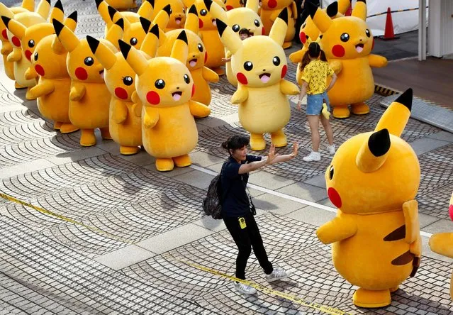 A staff guides a performer wearing Pokemon's character Pikachu costume as they prepare for a parade in Yokohama, Japan, August 7, 2016. (Photo by Kim Kyung-Hoon/Reuters)