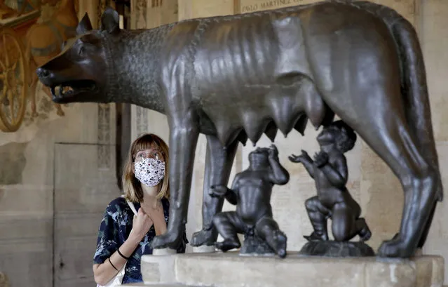 A visitor wearing a face mask to prevent the spread of COVID-19, looks at the statue of the She-Wolf nursing Romulus and Remus, the legendary founders of Rome, at Rome's Capitoline Museums, Tuesday, May 19, 2020. In Italy, museums were allowed to reopen this week for the first time since early March, but few were able to receive visitors immediately as management continued working to implement social distancing and hygiene measures, as well as reservation systems to stagger visits to museums in the onetime epicenter of the European pandemic. (Photo by Alessandra Tarantino/AP Photo)