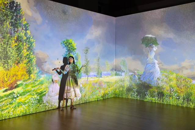 A woman stands next to paintings by french impressionist Claude Monet displayed on an Immersive Wall during a preview entitled 'En Voyage with Claude Monet. The First-ever Immersive Experience of Monet in Hong Kong' in Hong Kong, China, 15 September 2022. The immersive experience featuring works from the impressionist painter will bring more than 300 paintings to life through an application of light, sound and a 360 degrees animation when it opens on 27 October 2022. (Photo by Jerome Favre/EPA/EFE)