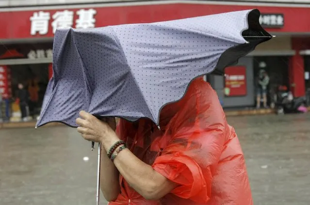A resident holding an umbrella walks against strong winds and heavy rainfall on a flooded street as Typhoon Kalmaegi hits Haikou, Hainan province, September 16, 2014. At least two people were killed after Typhoon Kalmaegi made landfall in south China on Tuesday morning, Xinhua News Agency reported. (Photo by Reuters/China Daily)