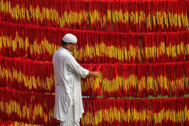 A workshop owner checks freshly-dyed “Kalawa threads”, a traditional sacred orange-yellow thread used in Hindu rituals, ahead of the Navratri festival at Lalgopalganj village some 45 kms from Allahabad on September 23, 2022. (Photo by Sanjay Kanojia/AFP Photo)