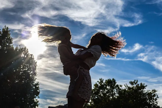 In this photograph taken on August 20, 2022 a woman dances with a child alongside the Garonne river in Toulouse, southern France. (Photo by Charly Triballeau/AFP Photo)