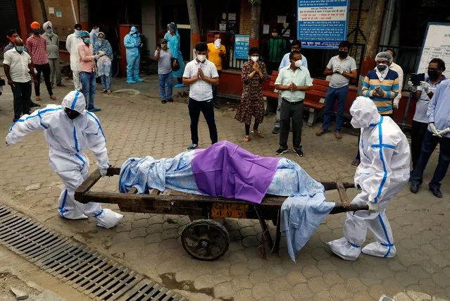 Health workers wearing Personal Protective Equipment (PPE) carry the body of a person who who died due to the coronavirus disease at a crematorium in New Delhi, India, June 24, 2020. (Photo by Anushree Fadnavis/Reuters)