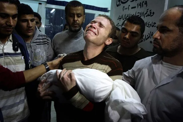 Jihad Masharawi weeps while he holds the body of his 11-month old son Ahmad following an Israeli air strike in Gaza City on Wednesday. (Photo by Majed Hamdan/Associated Press)