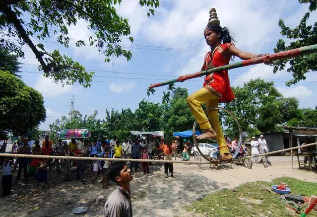 A girl performs a balancing act on a rope in Nagaon district in the northeastern state of Assam, India August 26, 2016. (Photo by Reuters/Stringer)