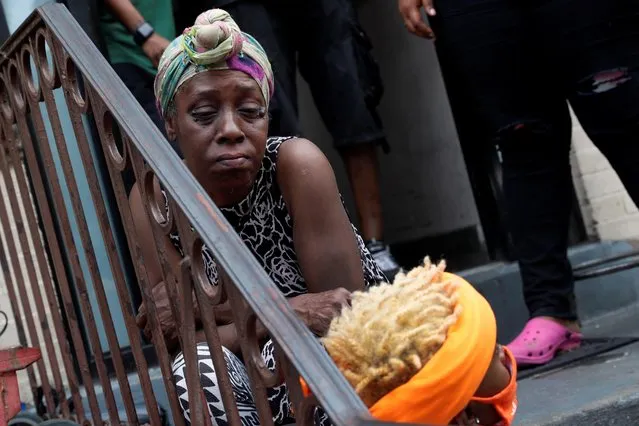 A woman grieves on the stoop of an apartment near the scene of the shooting, where a 1-year-old boy was shot and killed when gunfire erupted near the Raymond Bush Playground during a Sunday picnic, in the Brooklyn borough of New York, U.S., July 13, 2020. (Photo by Shannon Stapleton/Reuters)