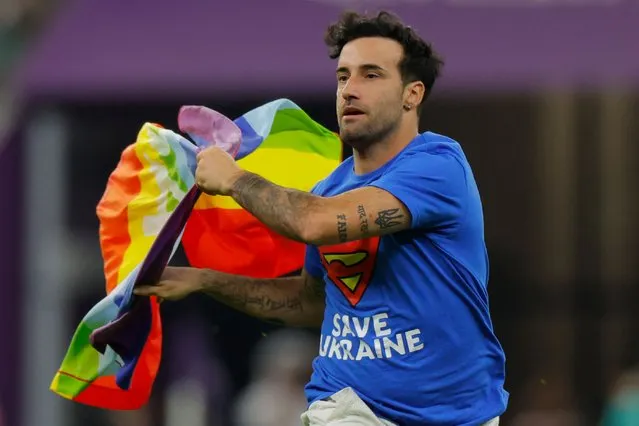 A man wearing a “Save Ukraine” t-shirt runs on the pitch waving a rainbow flag on the pitch during the Qatar 2022 World Cup Group H football match between Portugal and Uruguay at the Lusail Stadium in Lusail, north of Doha on November 28, 2022. (Photo by Odd Andersen/AFP Photo)
