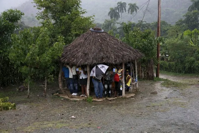 People take refuge from the rain under a hut after Pope Francis drove past in El Cobre, Cuba, September 21, 2015. (Photo by Carlos Garcia Rawlins/Reuters)