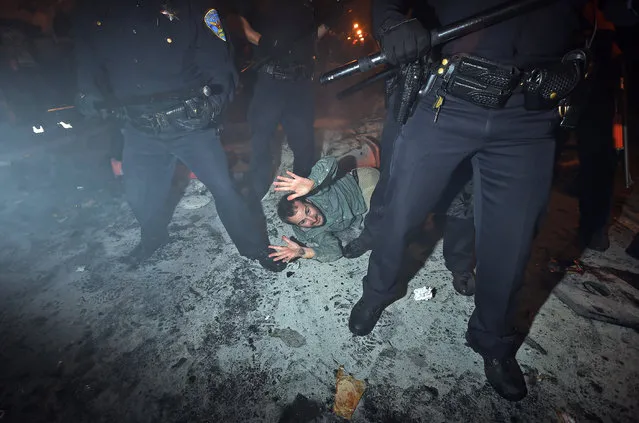 San Francisco police officers subdue a man who was seen driving a meter maid vehicle through the Mission district after the San Francisco Giants won the World Series baseball game against the Kansas City Royals on Wednesday, October 29, 2014, in San Francisco. (Photo by Noah Berger/AP Photo)