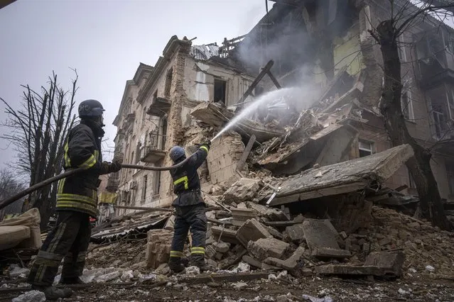 Ukrainian State Emergency Service firefighters work to extinguish a fire at the building which was destroyed by a Russian attack in Kryvyi Rih, Ukraine, Friday, December 16, 2022. Russian forces launched at least 60 missiles across Ukraine on Friday, officials said, reporting explosions in at least four cities, including Kyiv. At least two people were killed by a strike on a residential building in central Ukraine, where a hunt was on for survivors. (Photo by Evgeniy Maloletka/AP Photo)