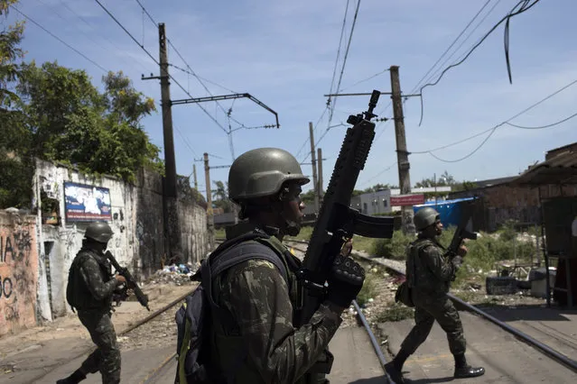 Soldiers take part in a surprise operation in the Jacarezinho slum in Rio de Janeiro, Brazil, Thursday, January 18, 2018. Troops have been sent to Rio due to the increase of the violence, and in an attempt to help restore order, but so far have had little impact. The operation on Thursday took place three weeks ahead of Carnival, when thousands of tourists are expected to arrive in the city. (Photo by Leo Correa/AP Photo)