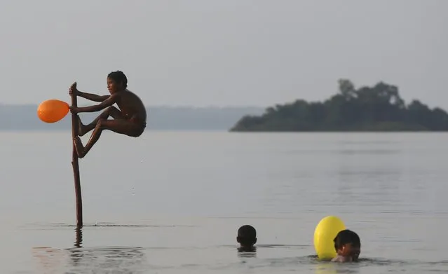 Indigenous children from the Kamayura tribe play with balloons in Ipavu lake at Xingu national park in Mato Grosso, Brazil, October 3, 2015. (Photo by Paulo Whitaker/Reuters)