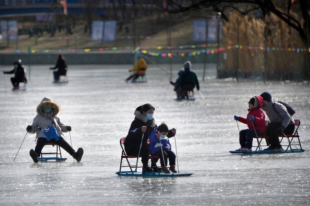 A woman and child push an ice chair across a frozen pond at a public park in Beijing, Tuesday, January 17, 2023. China has announced its first population decline in decades as what has been the world's most populous nation ages and its birthrate plunges. (Photo by Mark Schiefelbein/AP Photo)