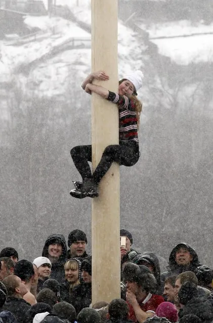 A woman reacts as she climbs up a smooth wooden column to win a contest during the celebrations of Maslenitsa, or Pancake Week, at the Bobrovy Log ski resort on the surburbs of Russia's Siberian city of Krasnoyarsk, March 17, 2013. Maslenitsa is widely viewed as a pagan holiday marking the end of winter and is celebrated with pancake eating, while the Orthodox Church considers it as the week of feasting before Lent. (Photo by Ilya Naymushin/Reuters)