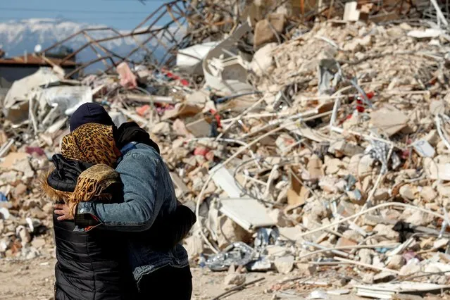 Grieving relatives embrace as rescuers work to extract the bodies of a father and his son from under the rubble in the aftermath of a deadly earthquake in Hatay, Turkey on February 14, 2023. (Photo by Clodagh Kilcoyne/Reuters)
