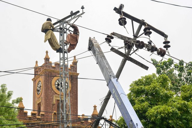 Technicians repair damaged electrical power lines in a residential area following heavy monsoon rains in Hyderabad, in Sindh province, on July 15, 2025. (Photo by Akram Shahid/AFP Photo)