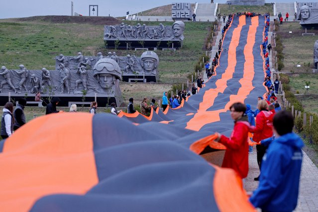 Participants hold a giant St. George's Ribbon at the memorial Savur-Mohyla (Saur-Mogila) during a ceremony marking the 79th anniversary of the victory over Nazi Germany in World War Two, in the course of Russia-Ukraine conflict in the Donetsk region, Russian-controlled Ukraine on May 8, 2024. (Photo by Alexander Ermochenko/Reuters)