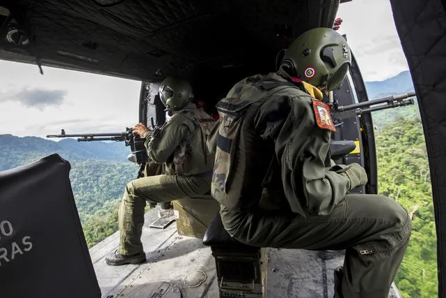 Venezuelan soldiers look out of a helicopter as they patrol during a military operation to destroy clandestine drug laboratories, near the border with Colombia, in the state of Zulia December 6, 2014. Perched on the northeast shoulder of South America with vast expanses of thinly-populated territory and a long Caribbean coast just a three-hour flight from Miami, Venezuela has many geographical advantages for traffickers. (Photo by Manaure Quintero/Reuters)