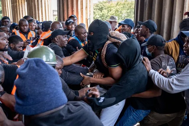 Demonstrating students and university security clash as they attempt to gain entry to the Great Hall at the University of the Witwatersrand (WITS) in Johannesburg on March 2, 2023. The students were protesting what they allege is a lack of adequate support from the university for unhoused students and those with outstanding fees. (Photo by AFP Photo/Stringer)
