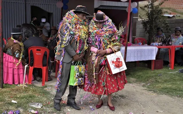 Carnival party hosts, Nelson Chavez and wife Laura Vargas, adorned with party streamers, await their guests during Challa Tuesday celebrations, in which devotees bury food, toss candies into the air and burn incense, all in a show of gratitude to Pachamama or Mother Earth, in Achocalla, Bolivia, Tuesday, February 21, 2023. The Andean ritual coincides with the Christian holiday Shrove Tuesday, the culmination of Carnival season, which officially begins each year on Jan. 6, the 12th day after Christmas, and closes with the beginning of Lent on Ash Wednesday. (Photo by Juan Karita/AP Photo)