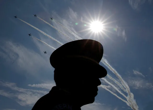 Japanese Self-Defence Forces' (SDF) official is silhouetted while flights performs air show during the annual SDF ceremony at Asaka Base, Japan, October 23, 2016. (Photo by Kim Kyung-Hoon/Reuters)