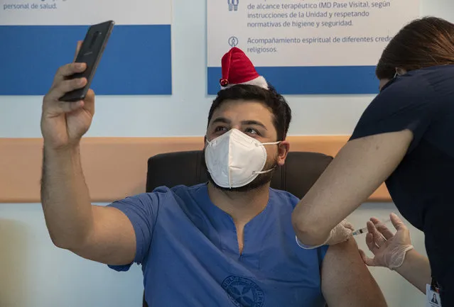 ICU Dr. German Osorio takes a selfie as he gets his COVID-19 vaccine shot at the Posta Central Hospital in Santiago, Chile, Thursday, December 24, 2020, on the same day the first shipment of vaccines arrived from Pfizer and its German partner, BioNTech. (Photo by Esteban Felix/AP Photo)