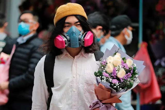 A man wears a gas mask as he holds a bouquet of flowers, following the outbreak of the novel coronavirus on Valentine’s Day in Hong Kong, China on February 14, 2020. (Photo by Tyrone Siu/Reuters)