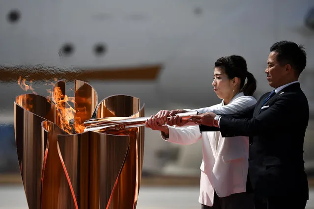 Japanese three-time Olympic gold medallists Saori Yoshida (L) and Tadahiro Nomura (R) light a Tokyo 2020 Olympic cauldron with the Olympic flame, after transporting the flame from Greece, at the Japan Air Self-Defense Force Matsushima Base in Higashimatsushima, Miyagi prefecture on March 20, 2020. The Olympic flame arrives in Japan on March 20, with what should have been a joyous celebration dramatically downscaled as doubts grow over whether the Tokyo Games can go ahead during the coronavirus pandemic. (Photo by Philip Fong/AFP Photo)