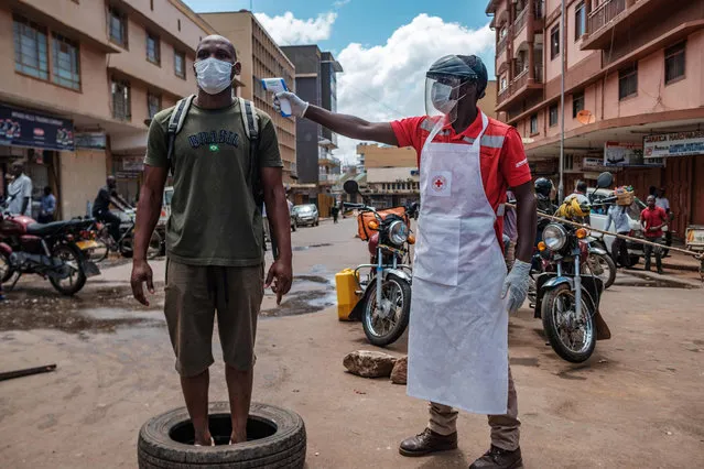 A Red Cross volunteer measures the temperature of a man before he can enter Nakasero market in Kampala, on April 1, 2020. Ugandan President Yoweri Museveni on March 30, 2020, ordered an immediate 14-day nationwide lockdown in a bid to halt the spread of the COVID-19 coronavirus which has so far infected 33 people in the country. (Photo by Sumy Sadurni/AFP Photo)