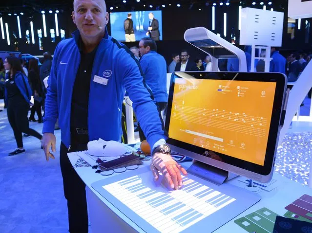 Colin Daymude plays music via a projected piano keyboard as he demonstrates the HP Sprout, January 6, 2015 at the Intel stand at the Consumer Electronics Show in Las Vegas, Nevada. The  Sprout is a “blended reality” PC which combines an all-in-one desktop PC with Intel's RealSense imaging technology, plus a combination scanner and projector, and a touch-sensitive projection surface called a Touchy Mat. (Photo by Robyn Beck/AFP Photo)