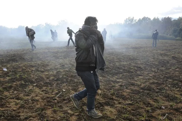 Stranded migrants run as tear gas fills the air during clashes with Macedonian police as they try to cross the Greek-Macedonian border, near the village of Idomeni, Greece  December 2, 2015. Picture taken from Greek side of the border. (Photo by Alexandros Avramidis/Reuters)